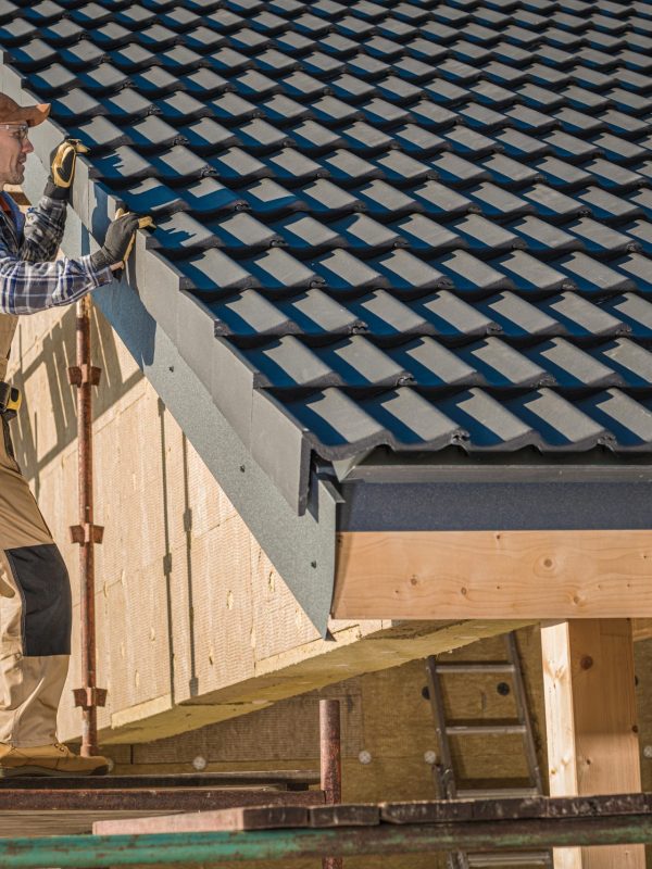 Professional Roofer Worker Finishing Ceramic Roof Tiles Installation. Smiling and Happy Worker on a Scaffolding.